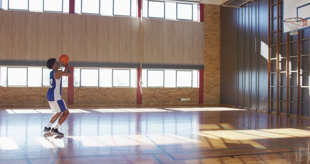 African american male basketball player practicing shooting with ball. basketball, sports training at an indoor court.