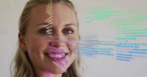 Smiling professional woman wearing pale top with projected code overlay in tech workspace