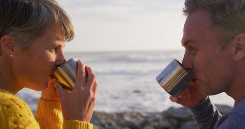 Senior couple enjoying coffee by the sea at sunset