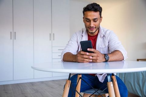 Young man using smartphone in minimalist modern apartment