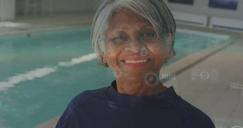 Smiling senior woman at indoor pool wearing swim shirt promoting active aging and wellness