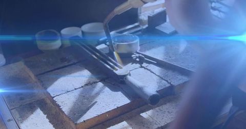 Heating crucible with torch for jewelry casting on firebrick bench, metalsmithing close-up