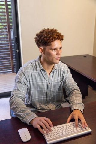 Young man engaged working on wireless keyboard in contemporary home office