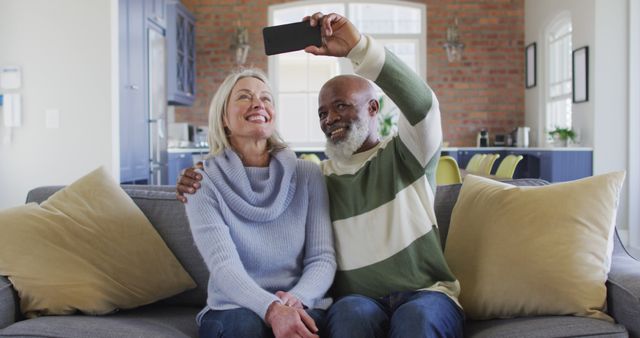 Happy senior diverse couple in living room sitting on sofa, using smartphone, making image call - Download Free Stock Photos Pikwizard.com