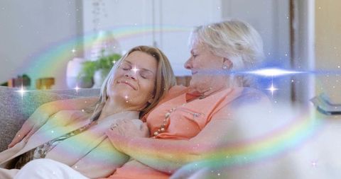 Mother and adult daughter embracing on sofa with pastel rainbow overlay and cozy vibe