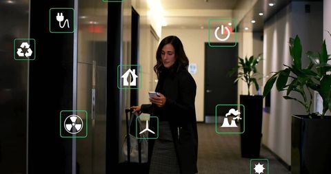 Business traveler walking hotel corridor pulling suitcase checking phone with green icons