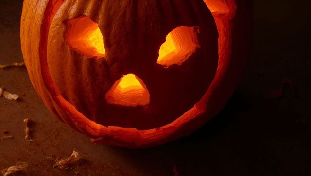 Glowing jack-o'-lantern illuminates dark halloween scene