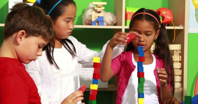 Children are using colorful building blocks to construct towers in a classroom environment. The kids are engaged in an educational and playful activity, encouraging teamwork and creativity. This image can be used for educational materials, advertisements for learning toys, classroom decorations, or parenting blogs.
