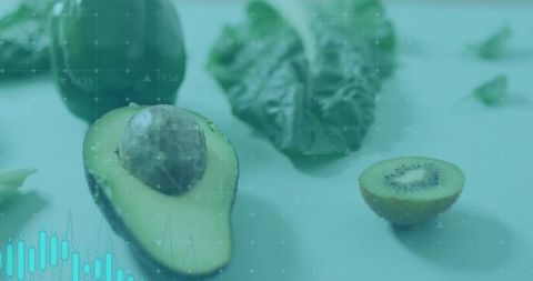 Halved avocado and kiwi with water droplets on minimal teal flatlay featuring grid overlay
