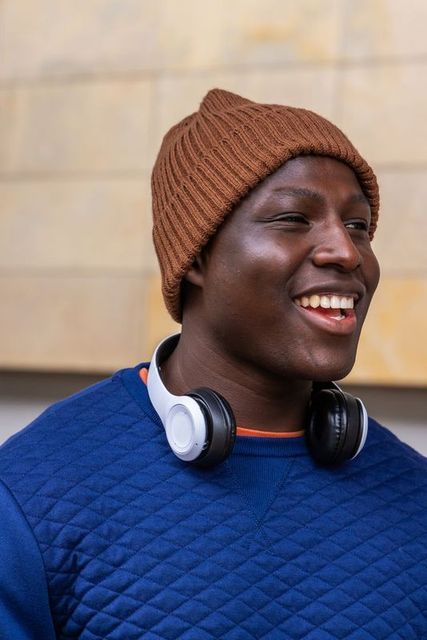 Cheerful african american young man wearing beanie and headphones urban closeup portrait
