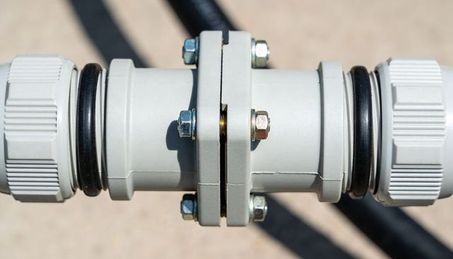 Close-up gray plastic pipe union with bolts and o-rings for plumbing connections