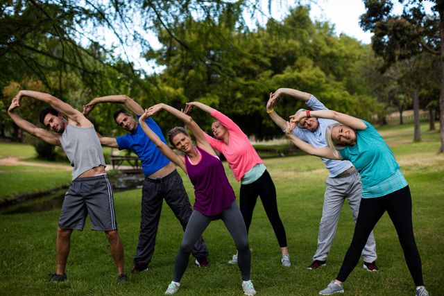 Group of people performing stretching exercise in park