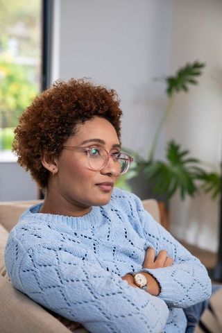 Thoughtful African American Woman Sitting on Sofa in Cozy Home