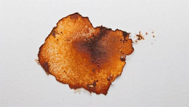 Peeling interior paint flaking on plaster with rust-colored stain and texture