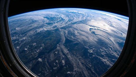Orbital porthole framing curved earth horizon with cloud swirls and atmosphere glow