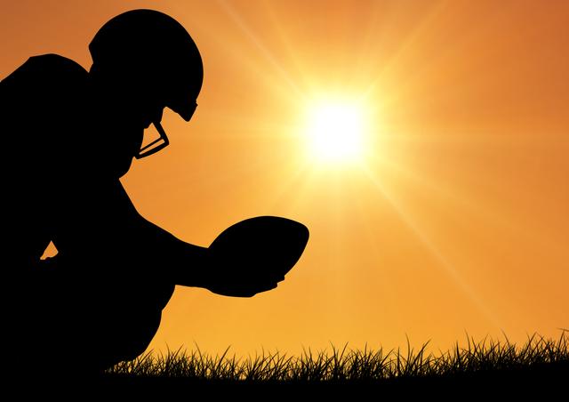 Silhouette of rugby player holding ball against bright sunlight