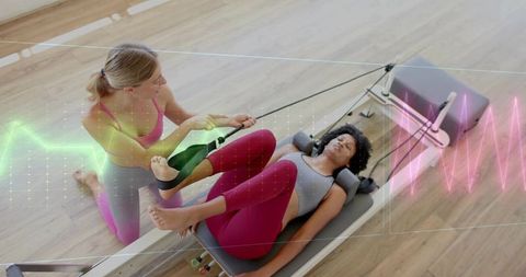 Trainer helping client on reformer pilates for core strength and movement alignment