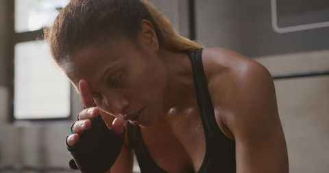 African american woman in gym wiping sweat after training