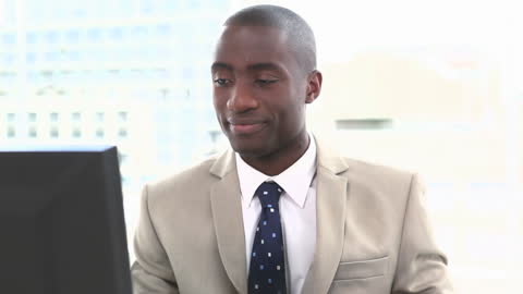 Confident Businessman Smiling While Working on Computer