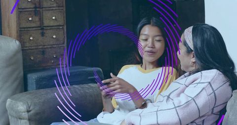 Asian mother and daughter chatting on couch with smartphone and purple circular overlay