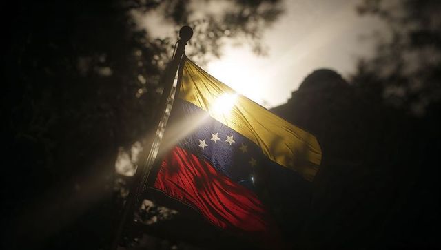 Venezuelan flag fluttering in backlight with sun flare and dramatic silhouette