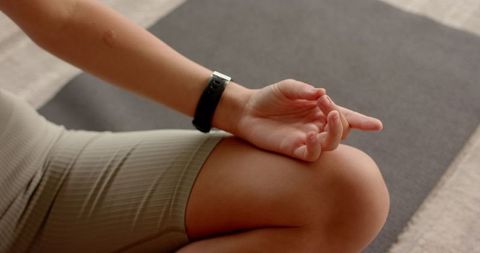 Woman Meditating in Living Room Wearing Smartwatch and Activewear