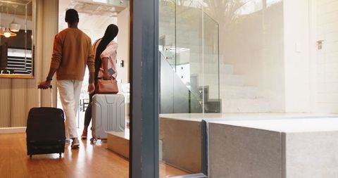 Couple enters modern home with luggage before travel adventure
