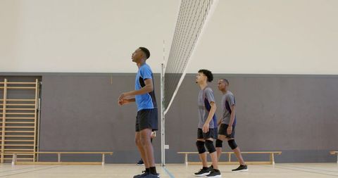 Male volleyball players practicing indoor gym by net training teamwork and athletic drills