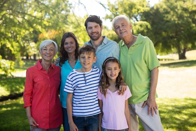 Multigenerational family smiling and bonding in a park on a sunny day. Ideal for use in advertisements, family-oriented content, lifestyle blogs, and promotional materials highlighting family values and outdoor activities.