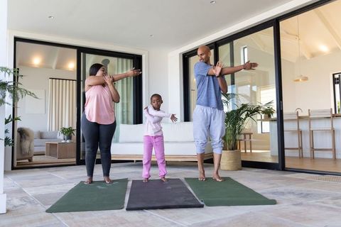 African american family stretching on patio yoga mats practicing morning fitness routine