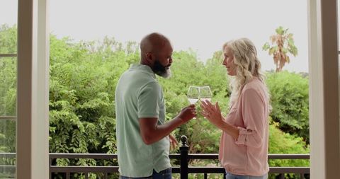Couple Sharing Wine on Balcony Overlooking Nature