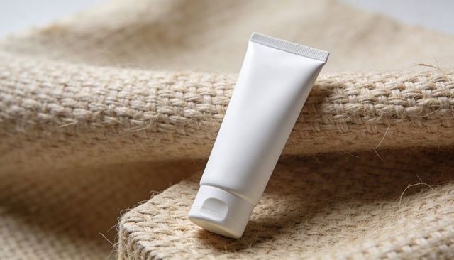 Blank white squeeze tube on jute fabric for skincare packaging mockup minimalist natural