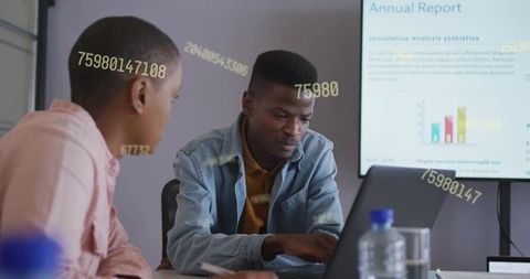 Young professionals collaborating on laptop during data analysis with numeric overlays