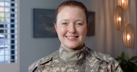 Proud female soldier smiling in military uniform indoors