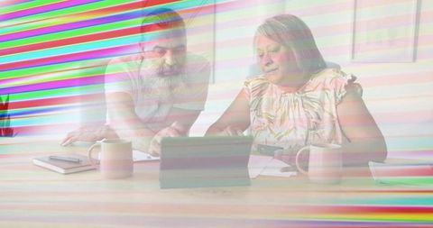 Senior couple reviewing bills and managing finances using tablet at home