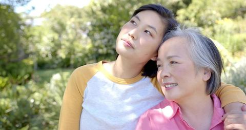 Mother and Daughter Leaning Together in Sunlit Garden Sharing Tender Intergenerational Bond