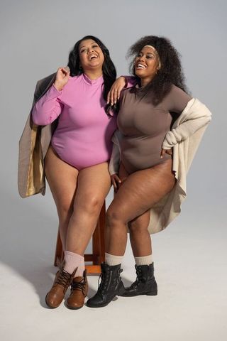 Curvy diverse friends laughing in bodysuits and cardigans celebrating body positivity