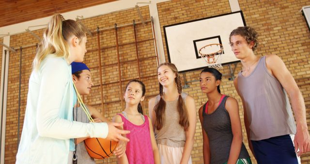 Female coach mentoring high school kids in basketball court - Download Free Stock Photos Pikwizard.com