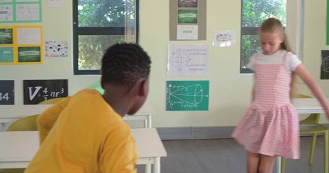 Elementary students leaning and turning in colorful classroom with geometry posters