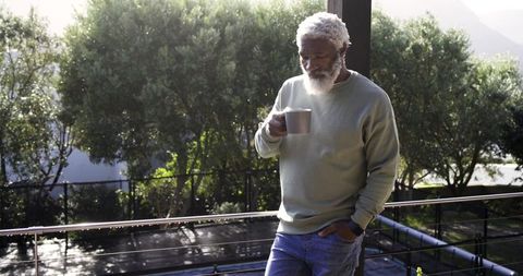 Mature Man Enjoying Morning Coffee on Balcony with Nature View