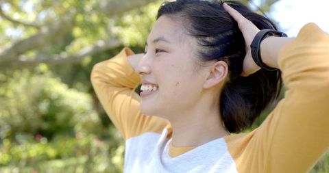 Relaxed Asian Woman Smiling Joyfully in Sunny Park