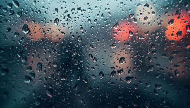Rain-Soaked Glass Blurring City Lights at Night