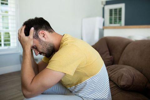 Pensive Man in Living Room Reflecting Thoughtfully on Sofa