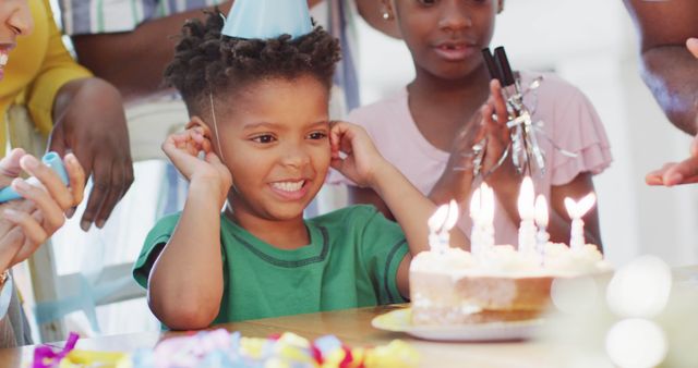 Captures joyful moment of young child celebrating birthday with cake and candles surrounded by family. Perfect for use in projects related to family celebrations, children's parties, birthdays, and moments of happiness.