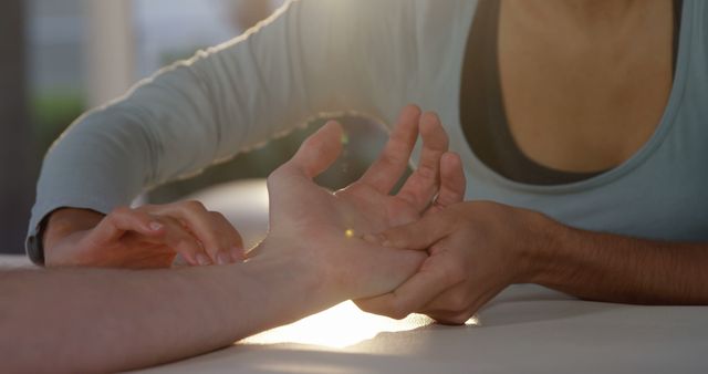 Closeup view of therapist providing hand massage therapy in sunlight. This image captures the essence of wellness and relaxation, making it ideal for promoting spa services, holistic healing practices, health and wellness content, and professional therapy services.