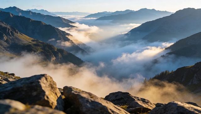 Foggy Alpine Valley Glowing in Golden Morning Light from Rocky Ridge with Mist-Filled Peaks