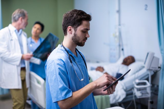 Male nurse using digital tablet during visit in ward