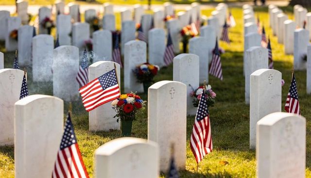 Sunlit military cemetery with american flags and patriotic bouquets honoring fallen soldiers