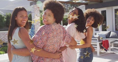 Smiling Diverse Women Linking Arms on Sunny Backyard Patio Celebrating Friendship