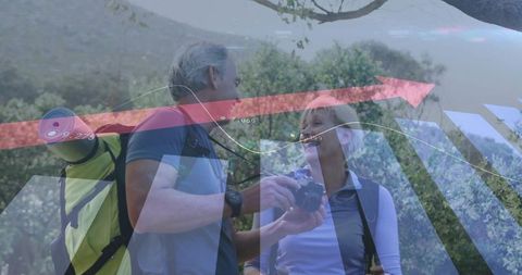 Mature couple hiking sharing camera shots with digital analytics overlay and upward arrow